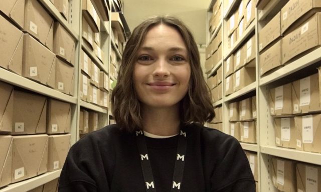Rebecca Keddie, graduate trainee archive assistant, standing in the archive store.