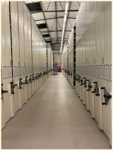 An image showing numerous rows of roller racking disappearing into the distance. A blue ladder at the far end is dwarfed by the height of the racks.