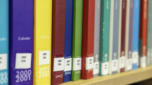 Shelf of University of Reading calendars by year, spines in different colours.